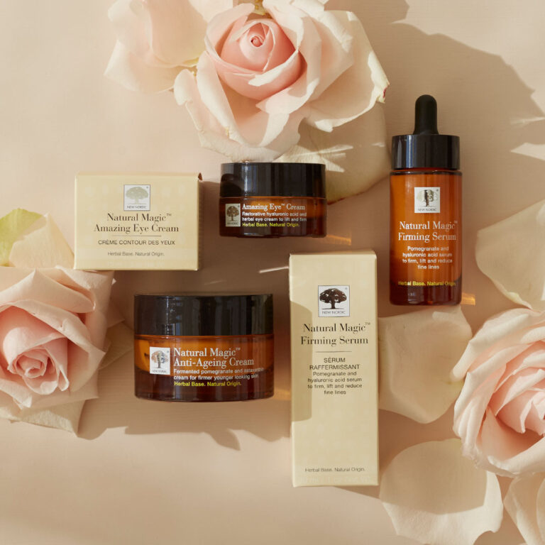 „Natural Magic™“ serijos produktai eksponuojami kartu su šviesiai rožinėmis rožėmis.