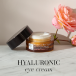 „Hyaluronic Active™“ akių kremas, eksponuojamas ant marmurinio stalo su rožine rože.